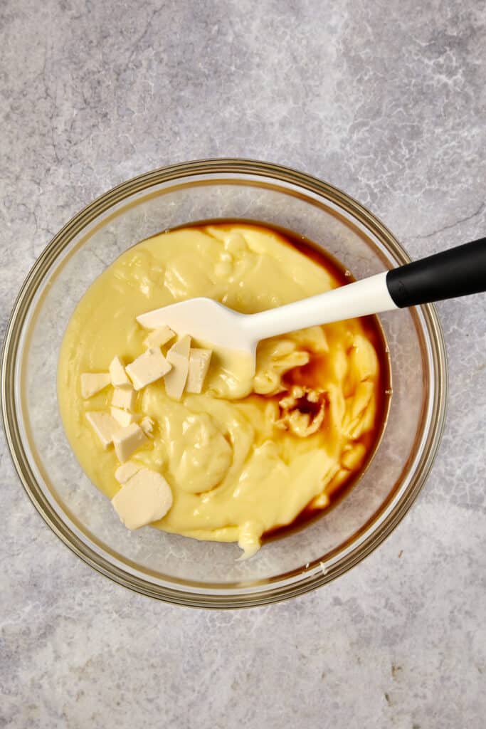 Overhead view of pudding with vanilla and butter in a glass bowl.