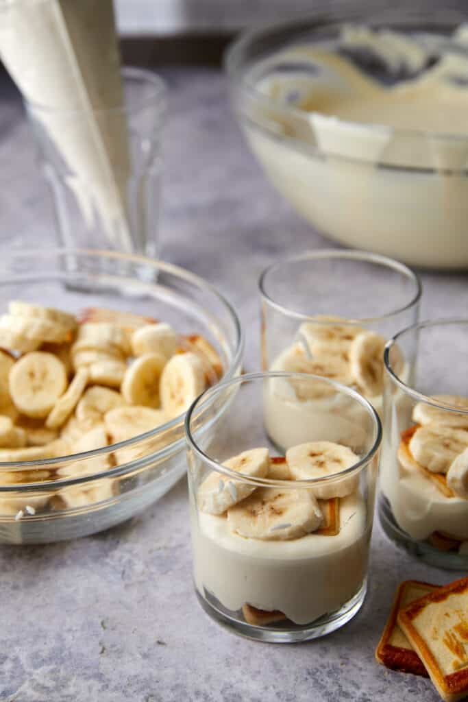 Glass cups layered with cookies, bananas, pudding, cookies, and bananas.