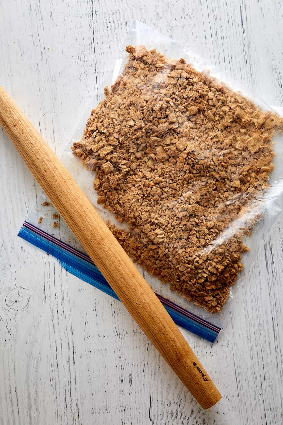 Overhead view of cereal in a plastic bag along side a rolling pin. 