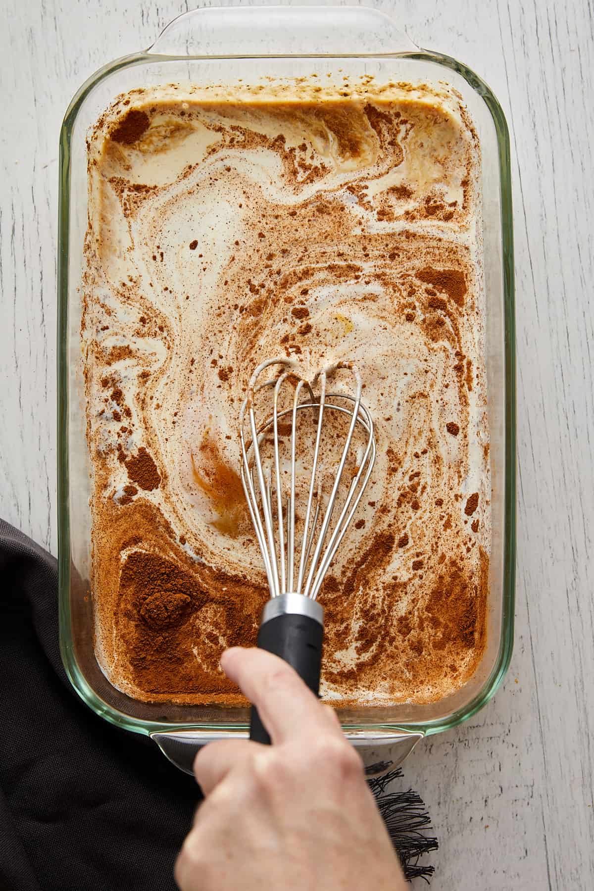 Overhead view of custard ingredients being mixed with a whisk.