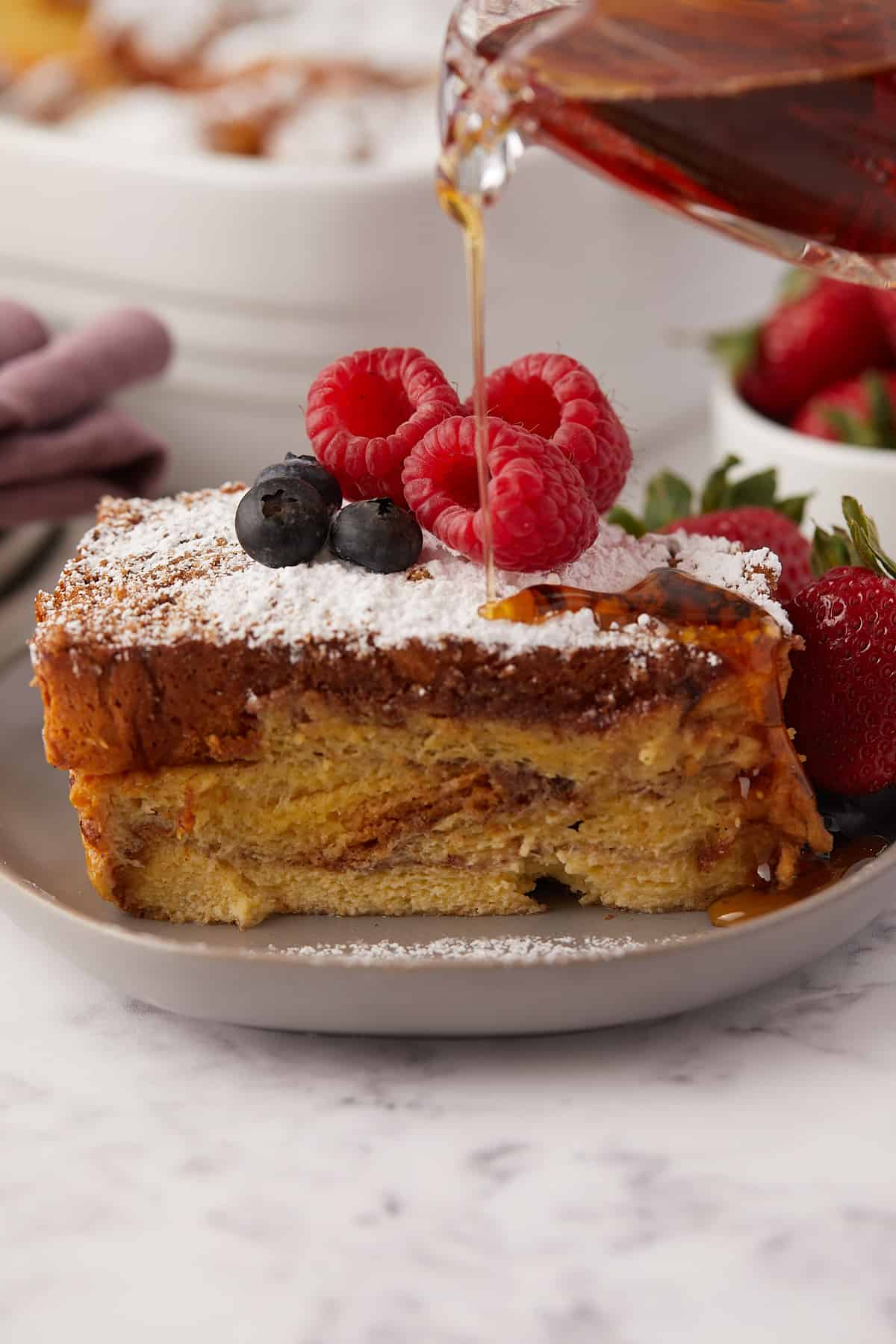 Front view of brioche french toast with maple syrup pouring on the top.