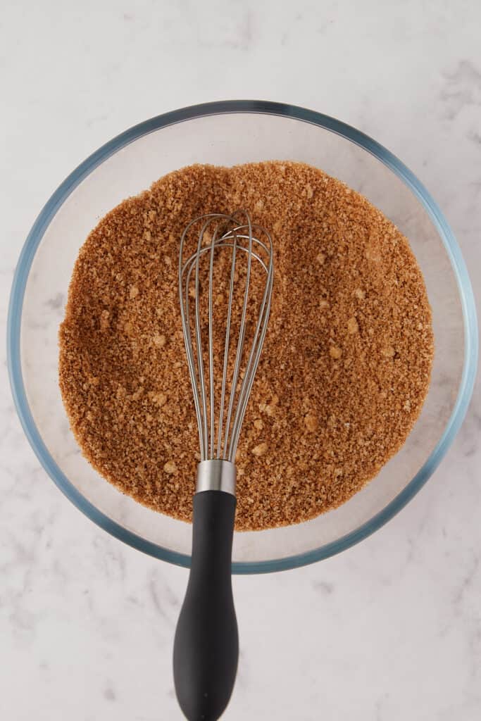 Overhead view of sugar and spices mixed with a whisk.