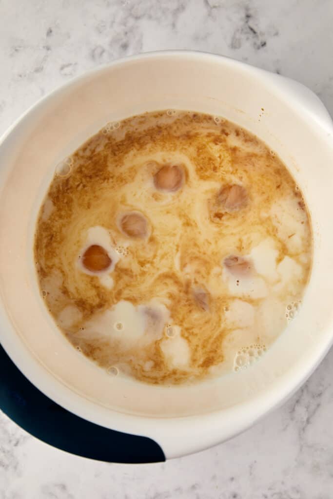 Overhead view of a plastic bowl with eggs, milk, and vanilla.