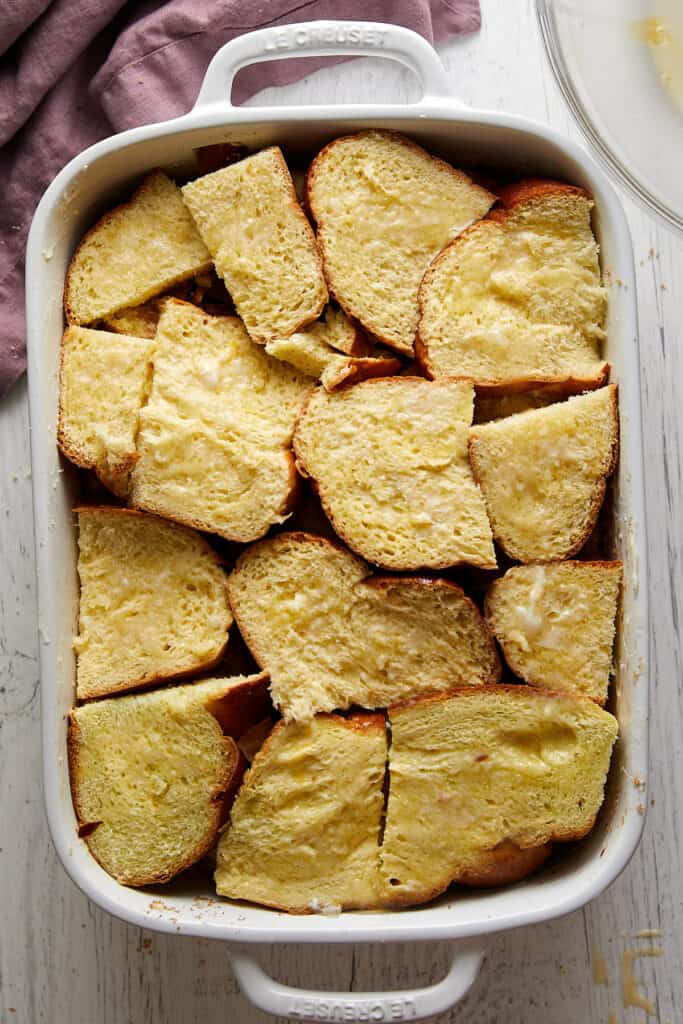 Challah french toast casserole with custard poured over the top of layers of bread.