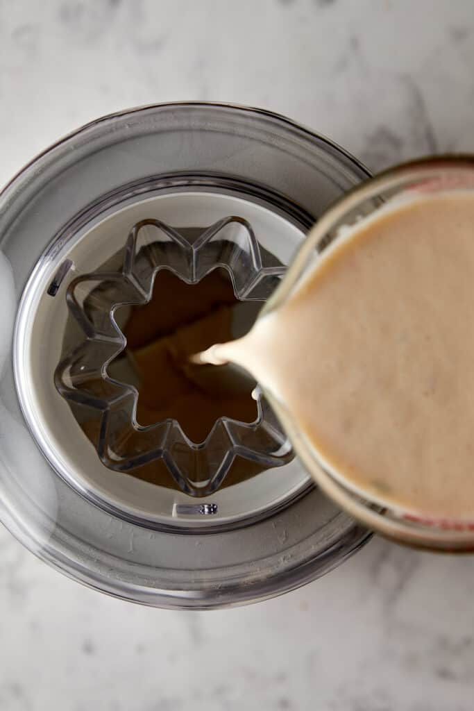 Overhead view of ice cream mixture being poured into ice cream machine. 