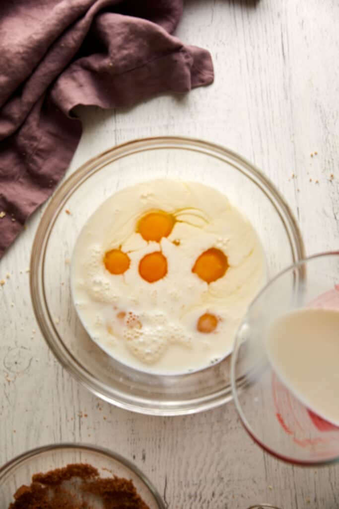 Overhead view of eggs with milk in a glass bowl.