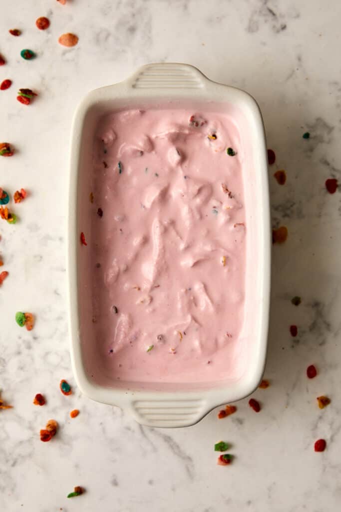 Overhead view of fruity pebble ice cream in white container.