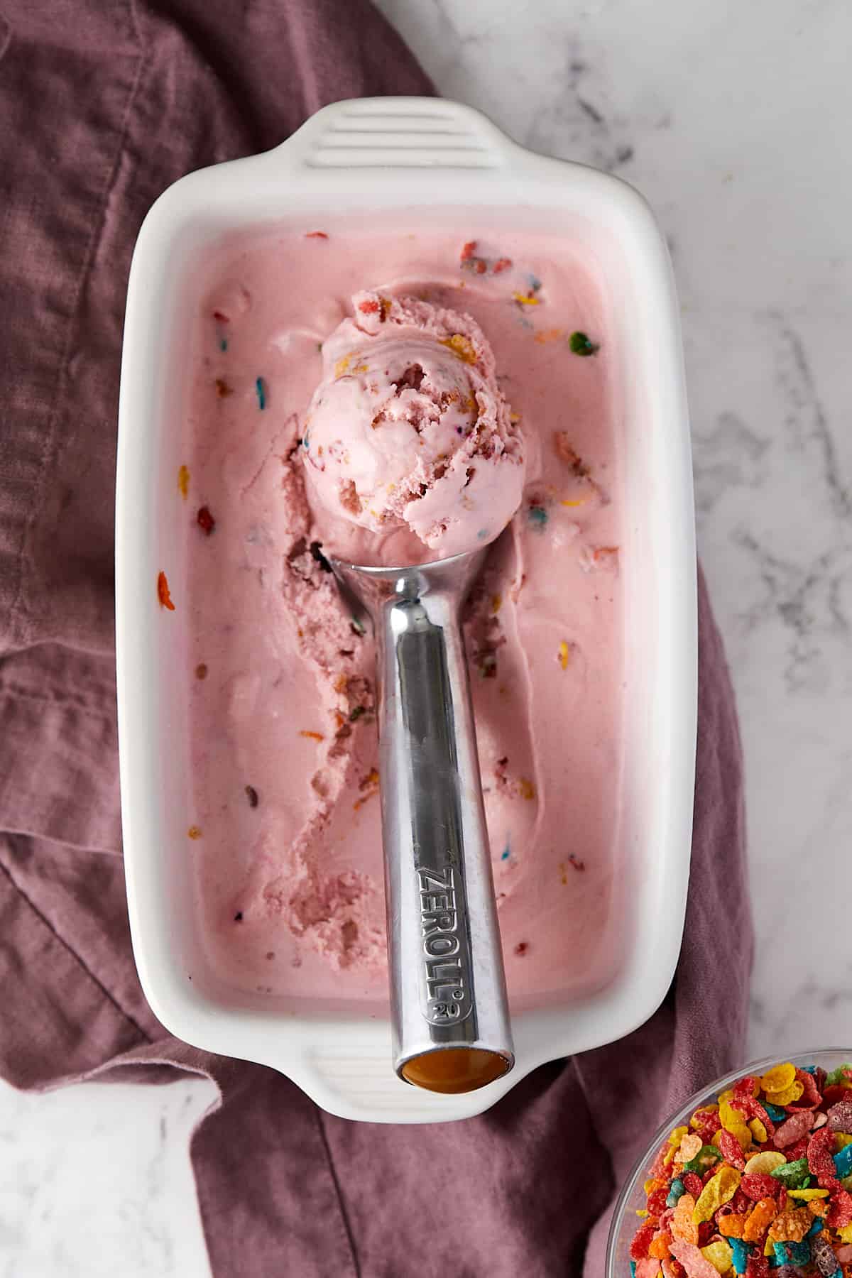 Fruity pebble ice cream with a scoop.