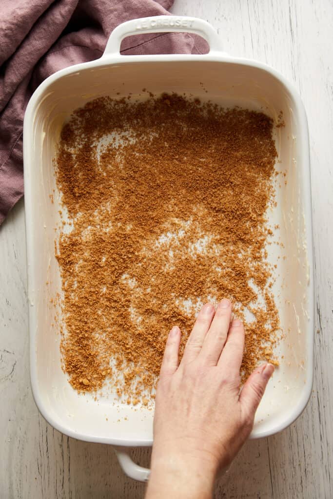 Brown sugar and spice mixture spread to the bottom of the pan with a hand.