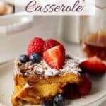 Close up view of challah french toast casserole on a plate with fruit on top.