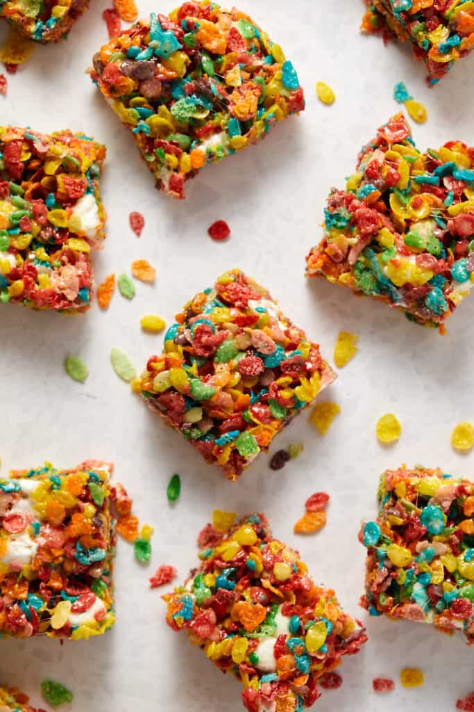 Overhead view of fruity pebbles and marshmallow treats cut into bars on a board.