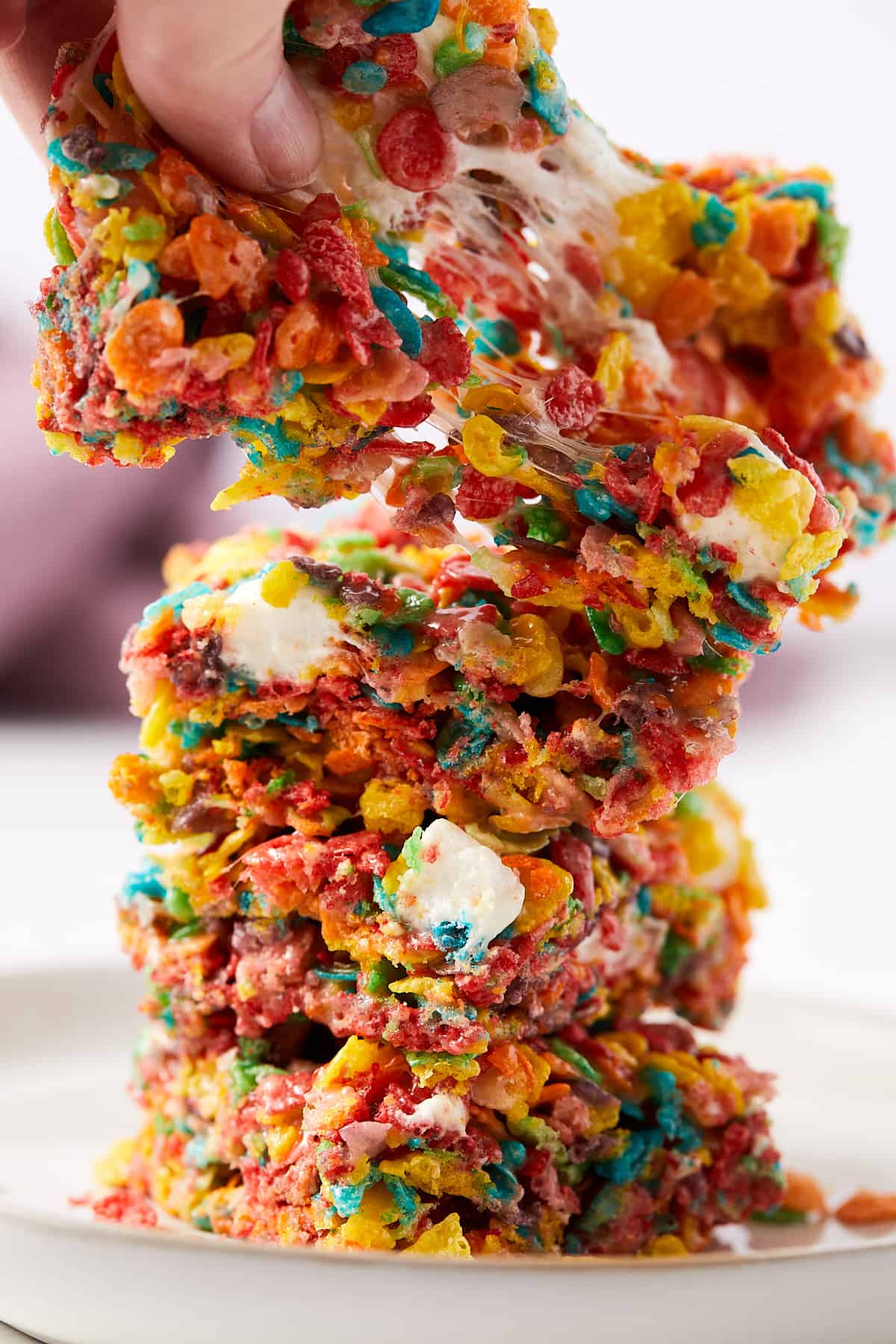 Fruity pebbles marshmallow treats stacked on top of each other with the top one being pulled a part.