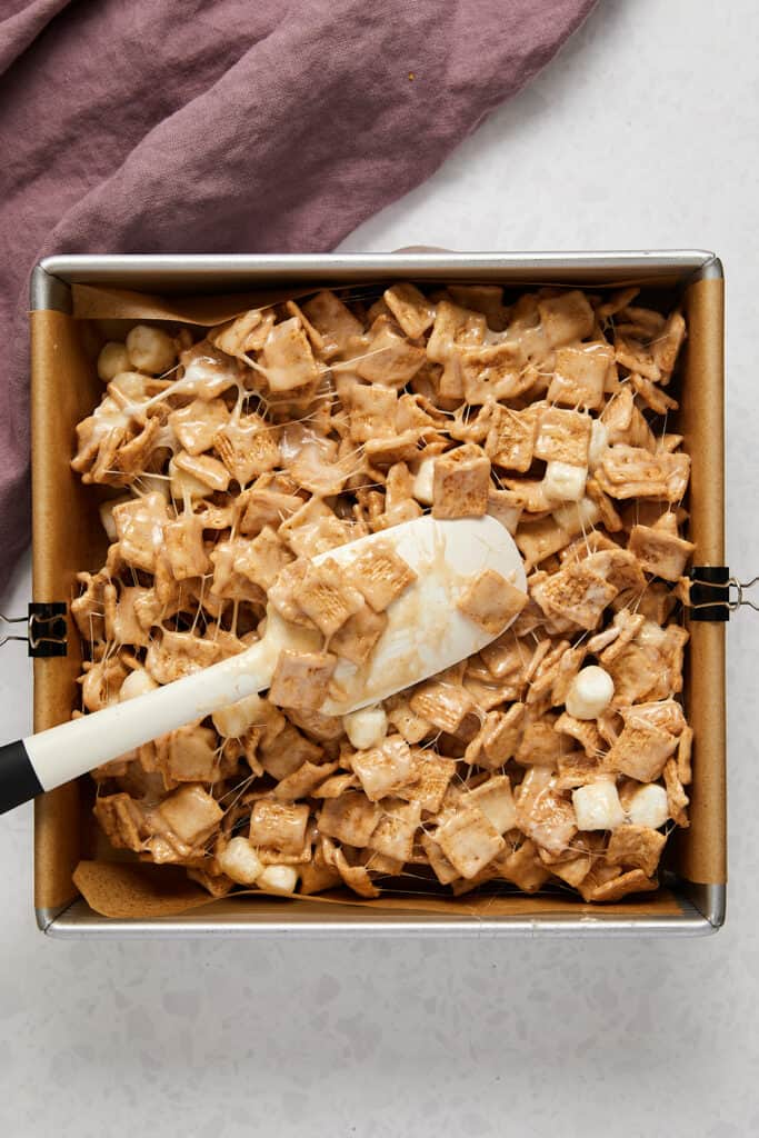 Overhead view of cinnamon toast crunch treats in pan with spatula. 