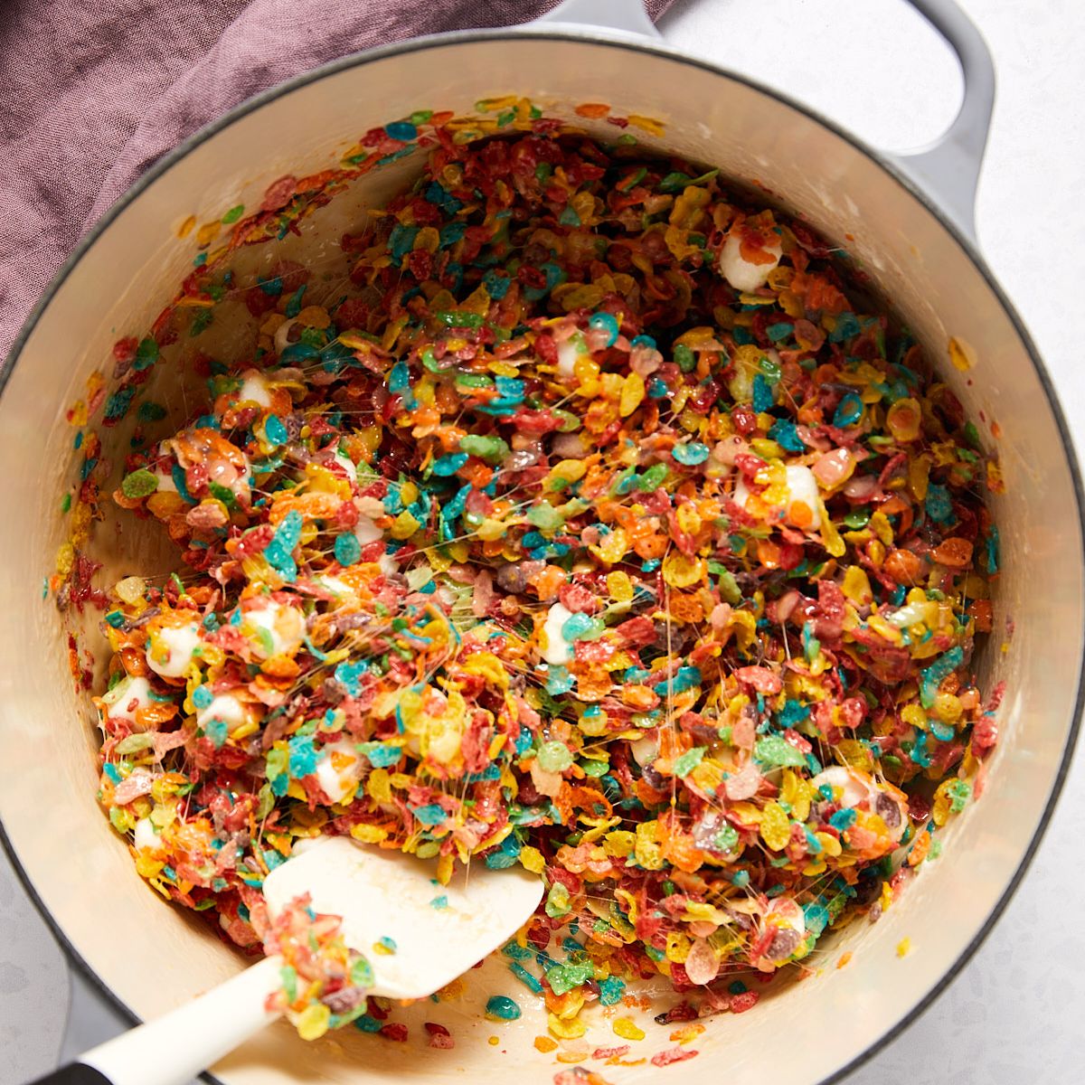 Rainbow Fruity Pebbles folded into melted marshmallow for fruity pebbles treats.