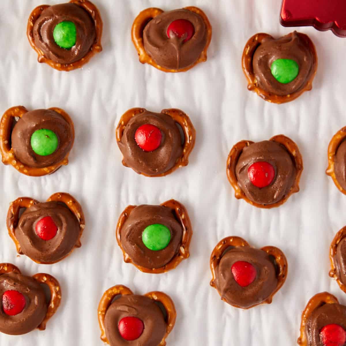 Overhead view of reindeer noses (rolo pretzel bites) on white parchment paper.