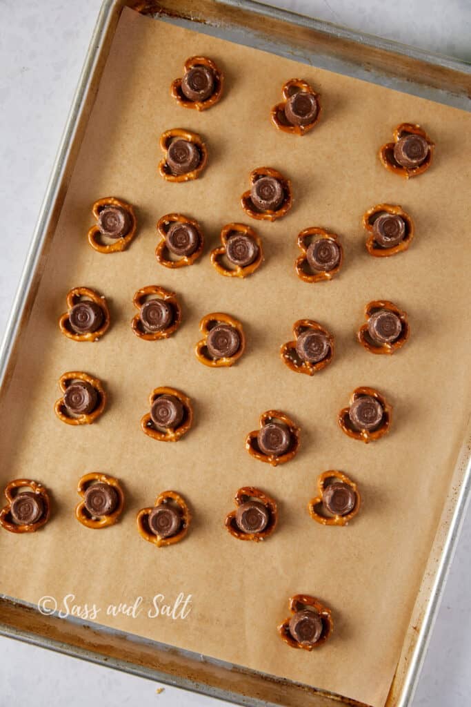 Rolos on top of each pretzel sitting on parchment paper on a sheet pan.