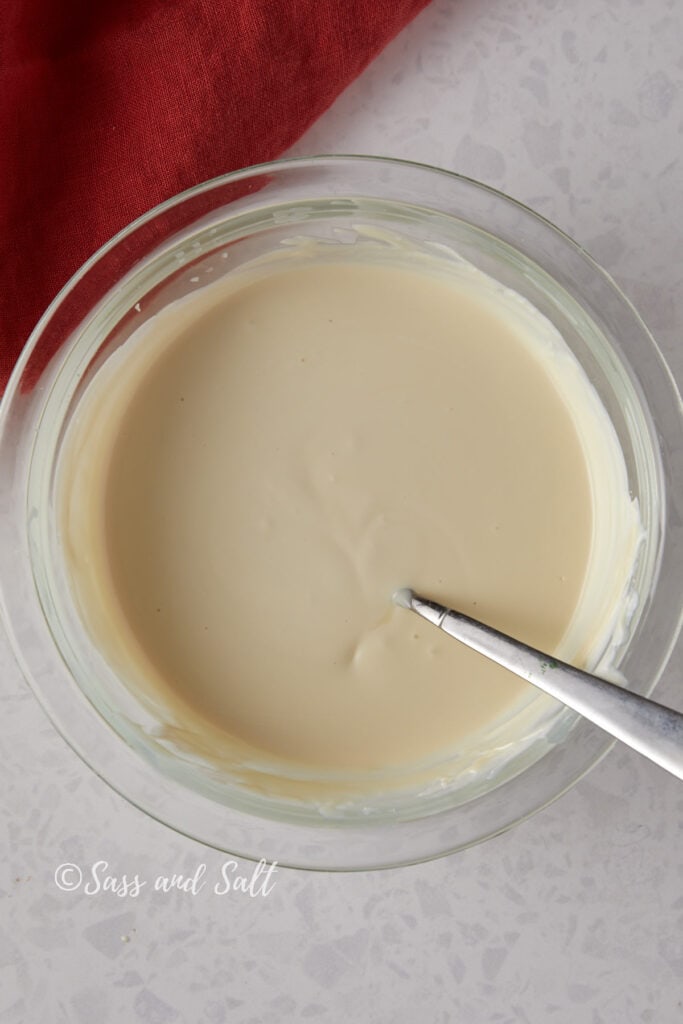 Overhead view of white chocolate melted in a glass bowl.