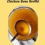 Alt text: A Pinterest pin featuring an overhead view of a clear glass bowl filled with homemade rotisserie chicken bone broth, with a ladle partially submerged, set against a warm yellow background. The text "Warm up with our homemade Rotisserie Chicken Bone Broth!" is displayed in a playful font above, and the website "www.thesassandsalt.com" is mentioned at the bottom.