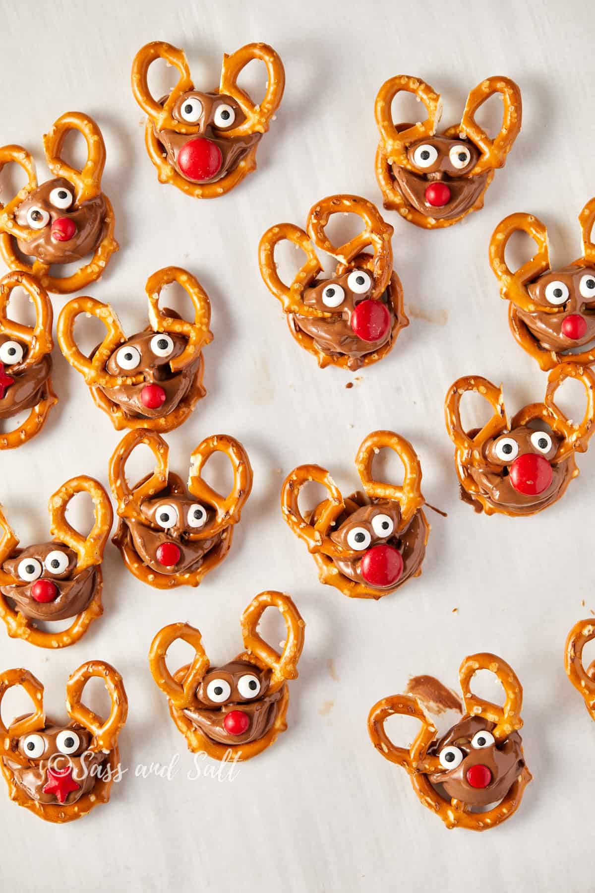 Overhead view of homemade Rolo pretzel reindeer treats with antlers, eyes, and red noses.