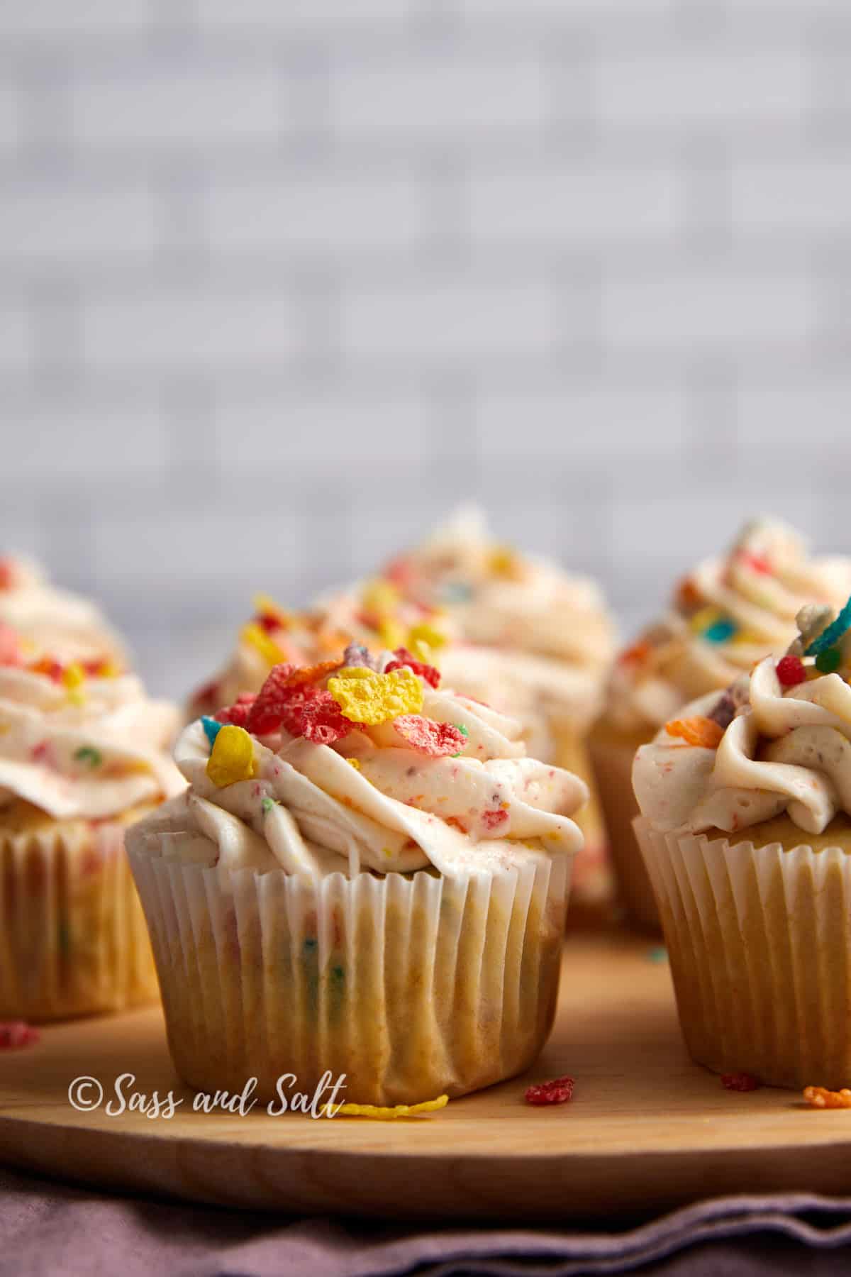 close up view of fruity pebbles cupcakes on wooden plate.