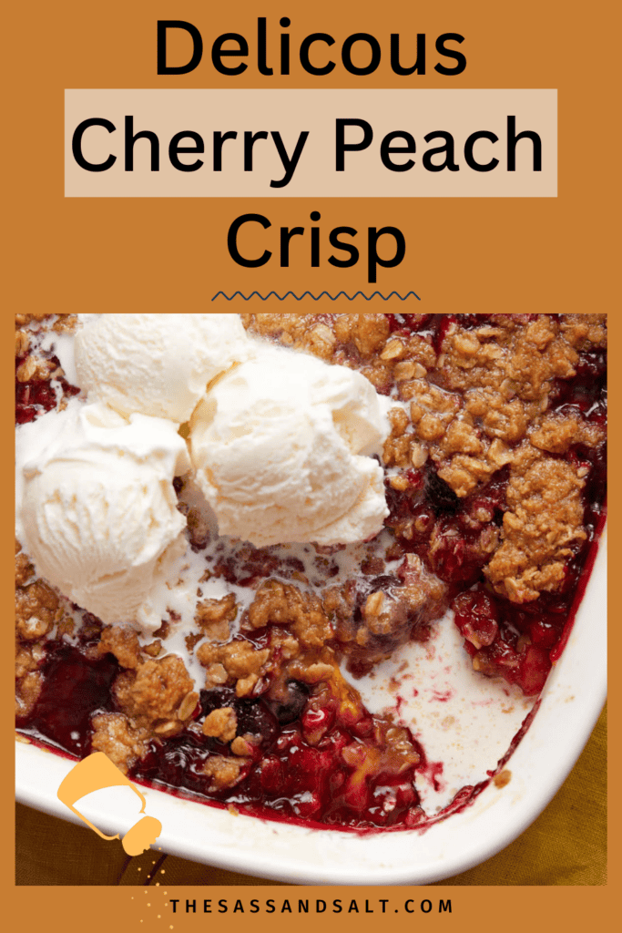 A cherry peach crisp topped with scoops of vanilla ice cream, featuring a golden-brown crumble topping and vibrant red fruit filling, served in a baking dish. the image includes the text "delicious cherry peach crisp" and the website "thesassandsalt.com".