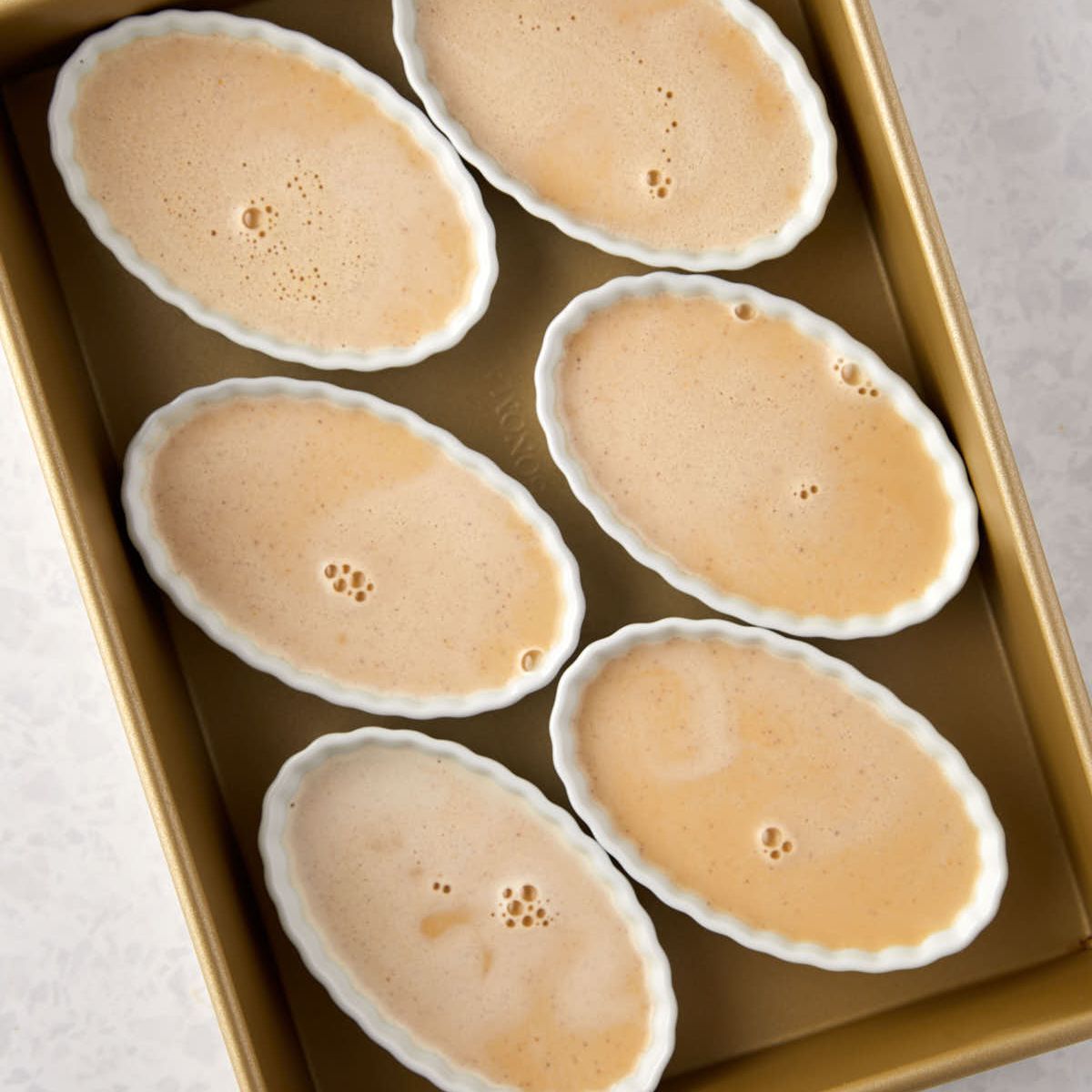 Pumpkin custard poured into ramekins before baking.