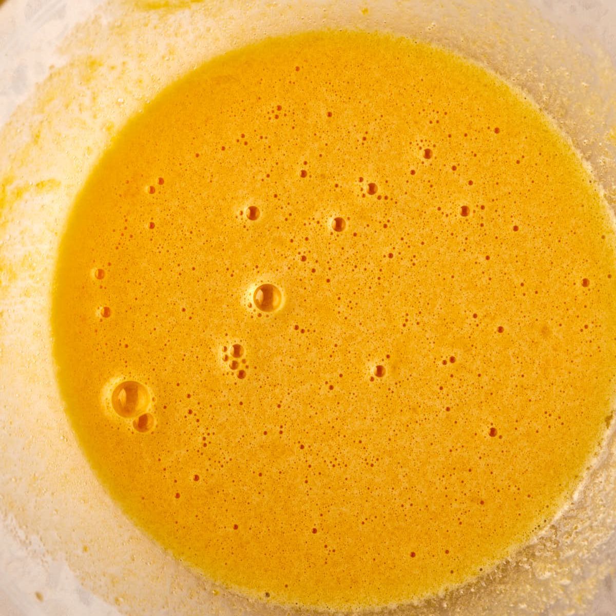 Egg yolks and sugar whisked in a bowl.