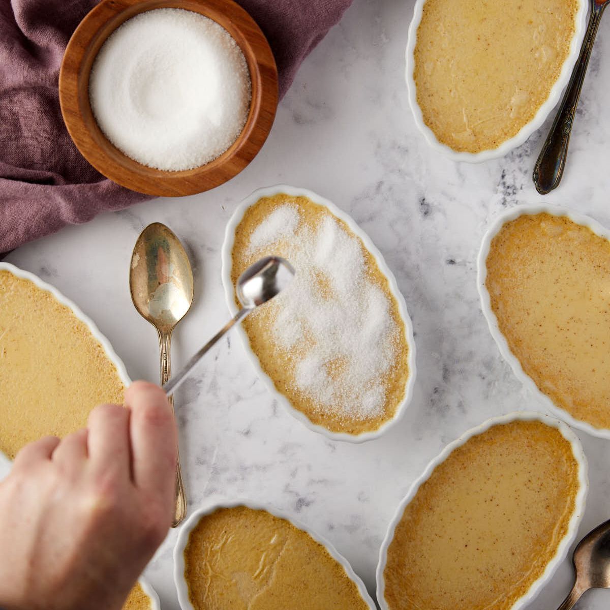 Sprinkling sugar over a baked pumpkin creme brulee.