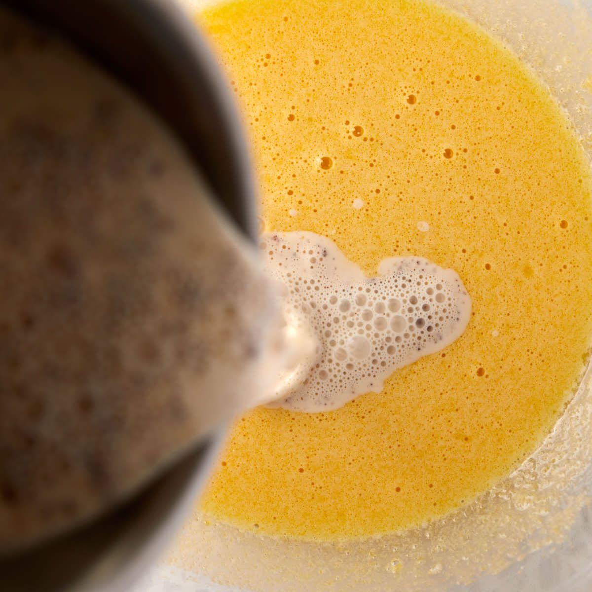Pouring warm spiced cream into the egg yolks.