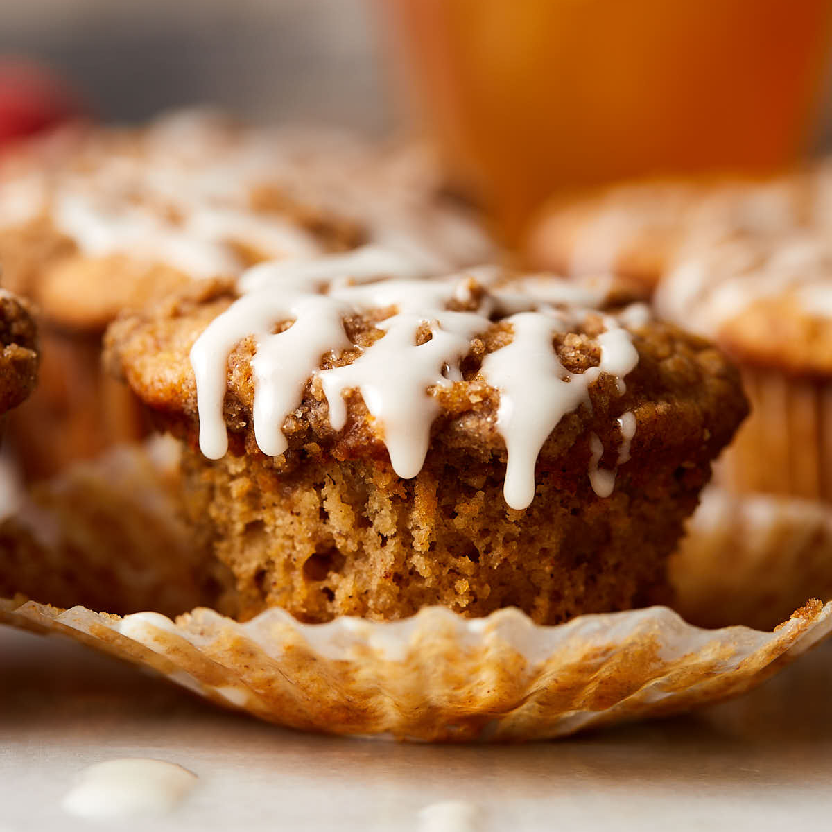 Vanilla icing drizzled over apple cider streusel muffins.