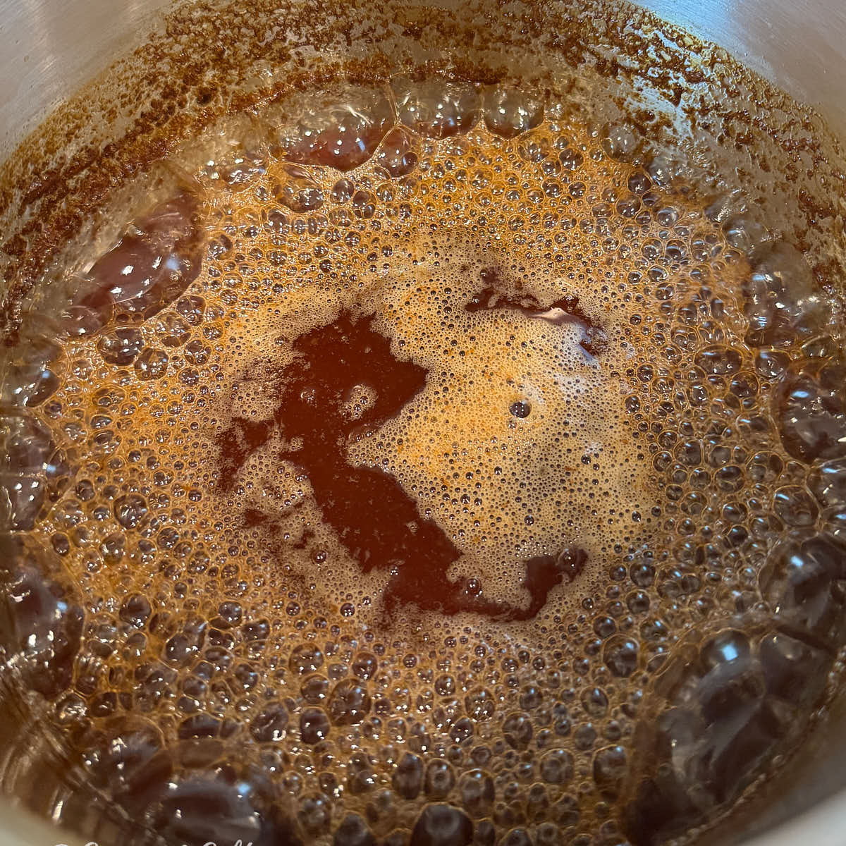 Apple cider reduction simmering and thickening in the pot.
