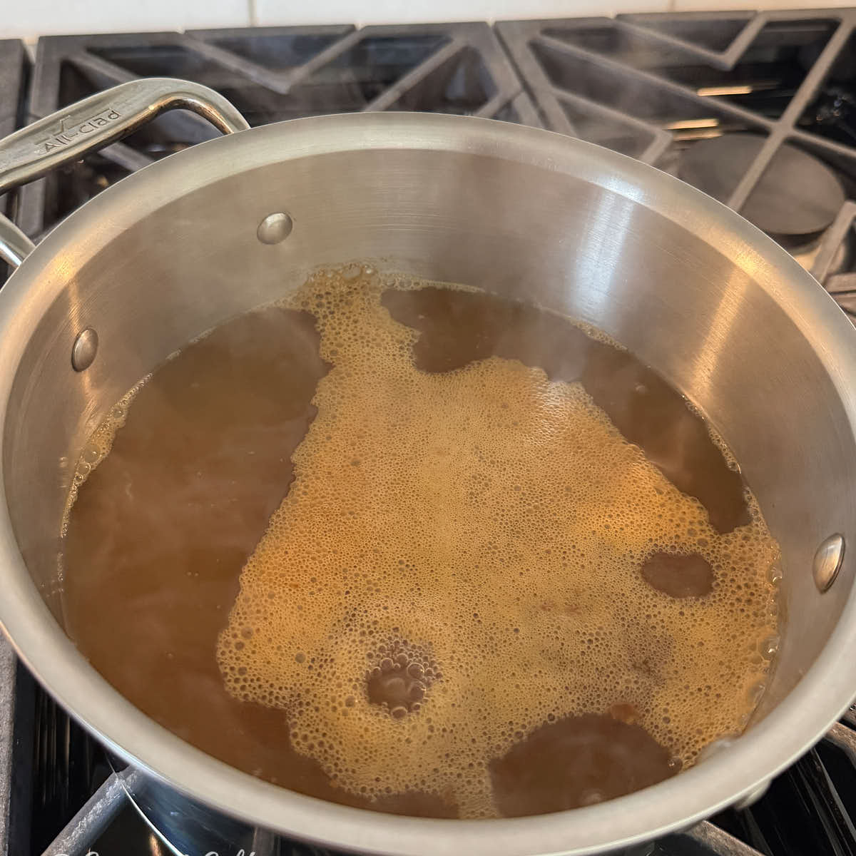 Apple cider boiling in a saucepan for boiled cider.