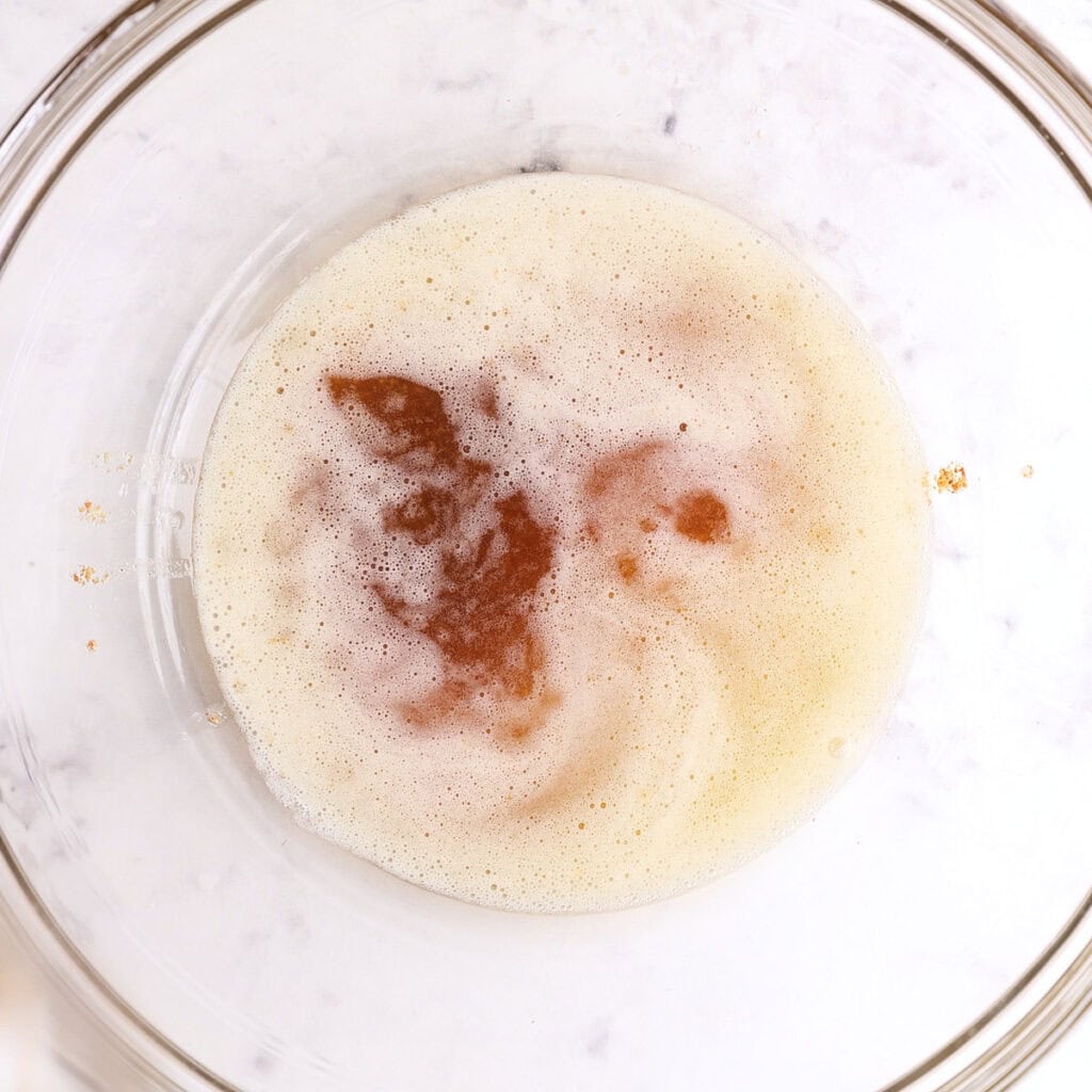 A glass mixing bowl containing melted browned butter.