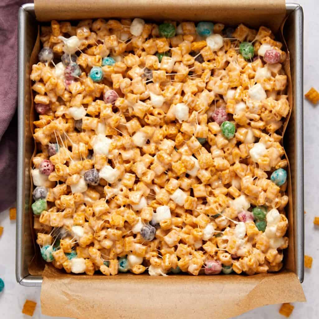 Captain Crunch marshmallow treats pressed into a parchment-lined baking pan.
