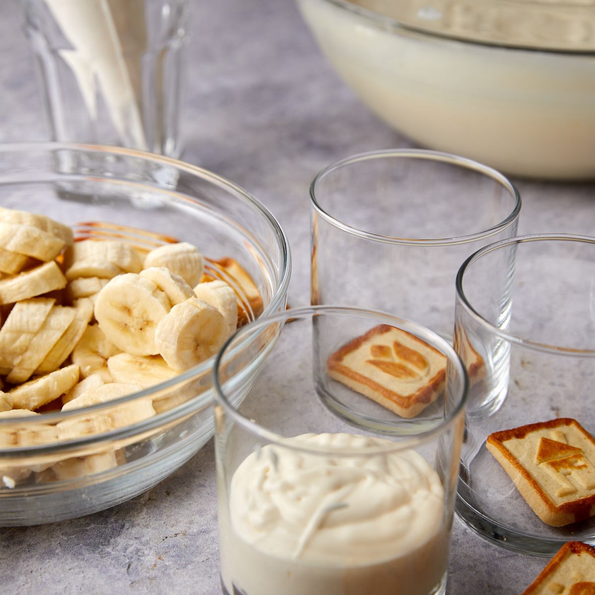 A layer of pudding spread over banana slices in a banana pudding cup.
