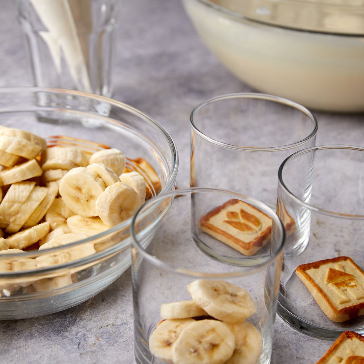 A Chessmen cookie and banana slices layered in the bottom of a glass for banana pudding cups.