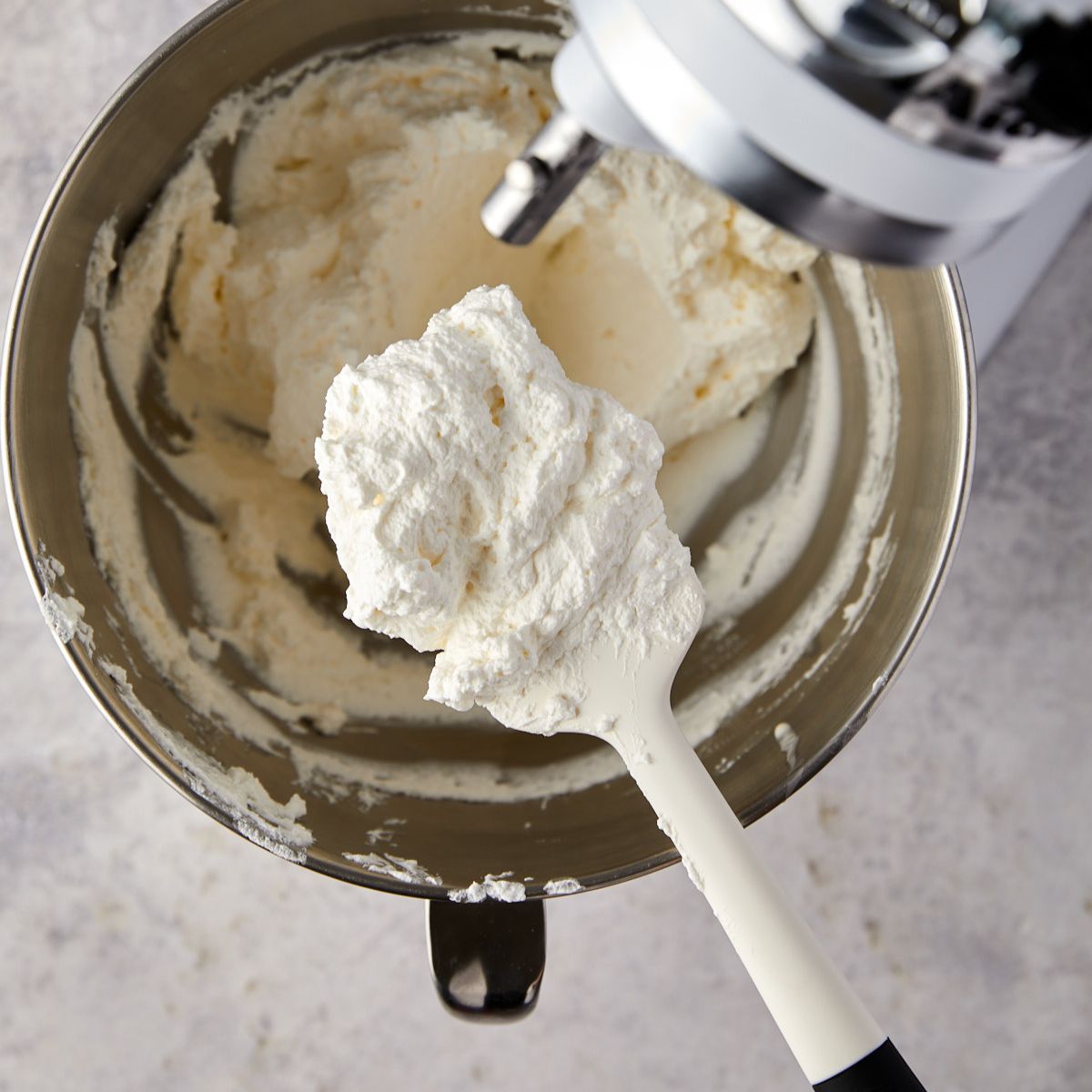 Heavy cream whipped to soft peaks in a stand mixer bowl.