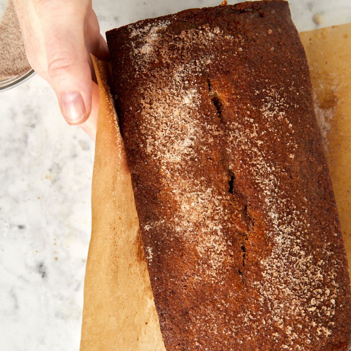 Coating apple cider donut loaf with cinnamon sugar.