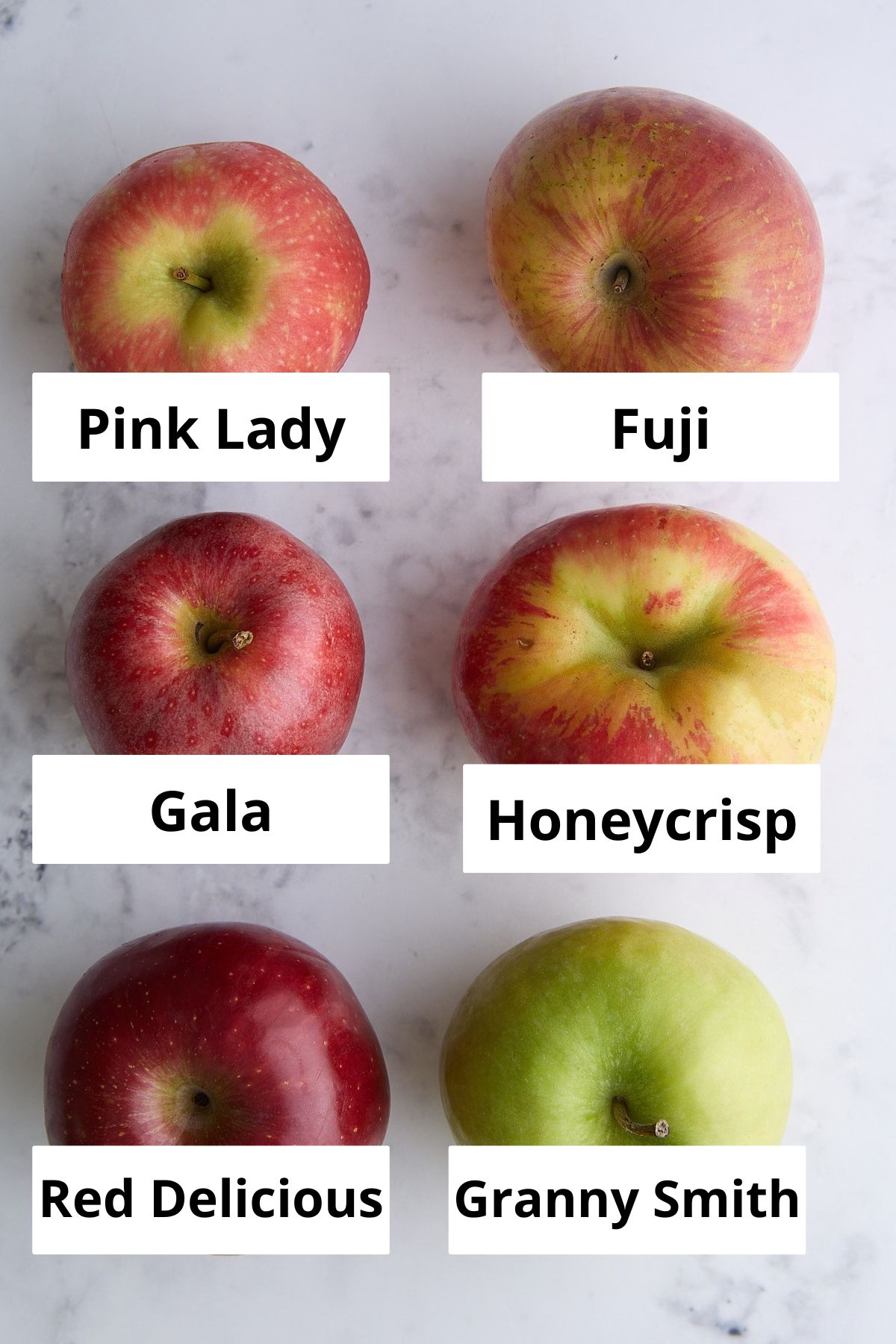 Six apples of different varieties are labeled: Pink Lady, Fuji, Gala, Honeycrisp, Red Delicious, and Granny Smith, arranged in two columns on a white surface.
