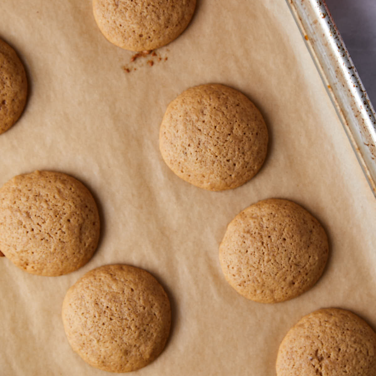 Baked whoopie pie cookies cooling on parchment lined sheet.