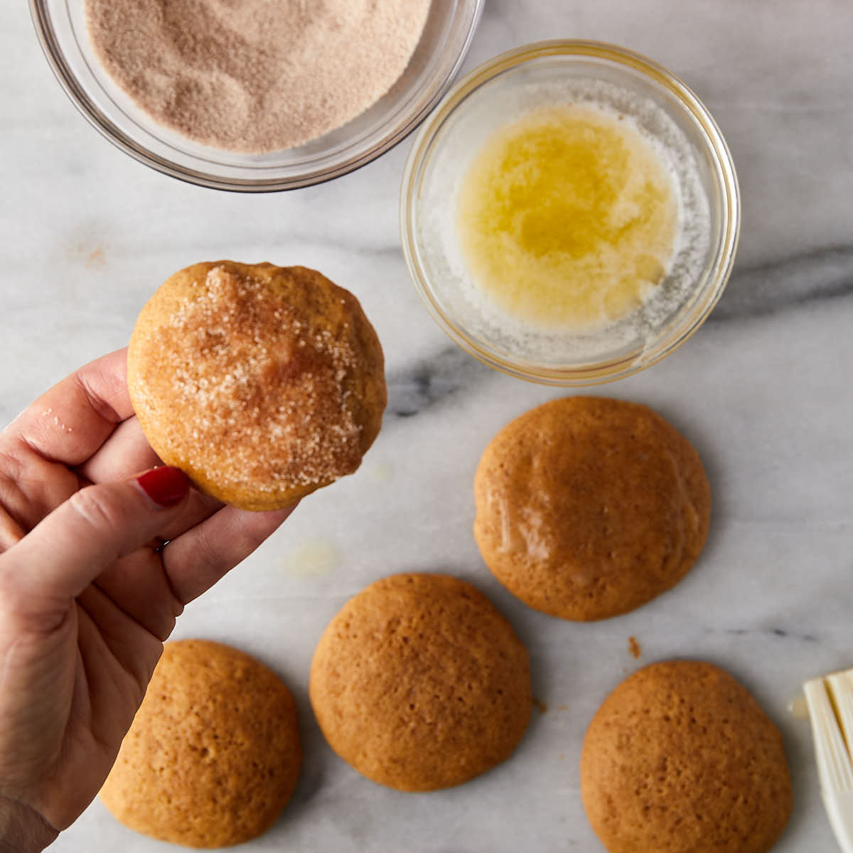 Dipping whoopie pie cookie in cinnamon sugar.