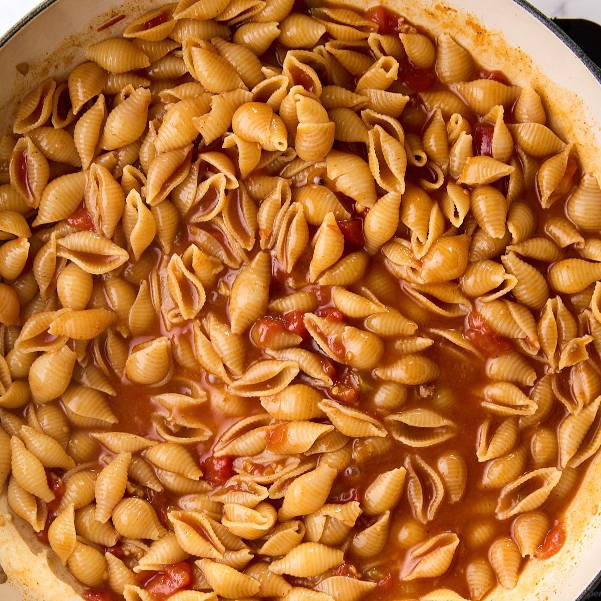 Pasta shells simmered until tender, with most of the liquid absorbed.