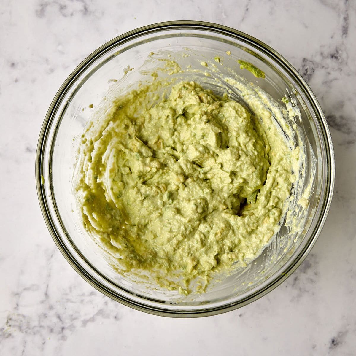Avocado cream made with mashed avocado and sour cream in a glass bowl.