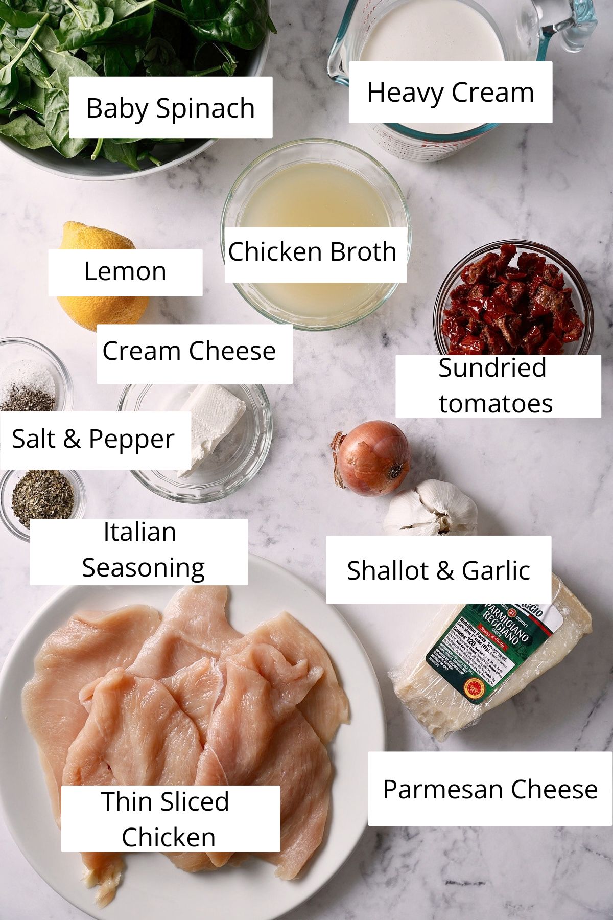 Chicken cutlets, spinach, cream, sun-dried tomatoes, parmesan, garlic, and shallot arranged in bowls on a counter.