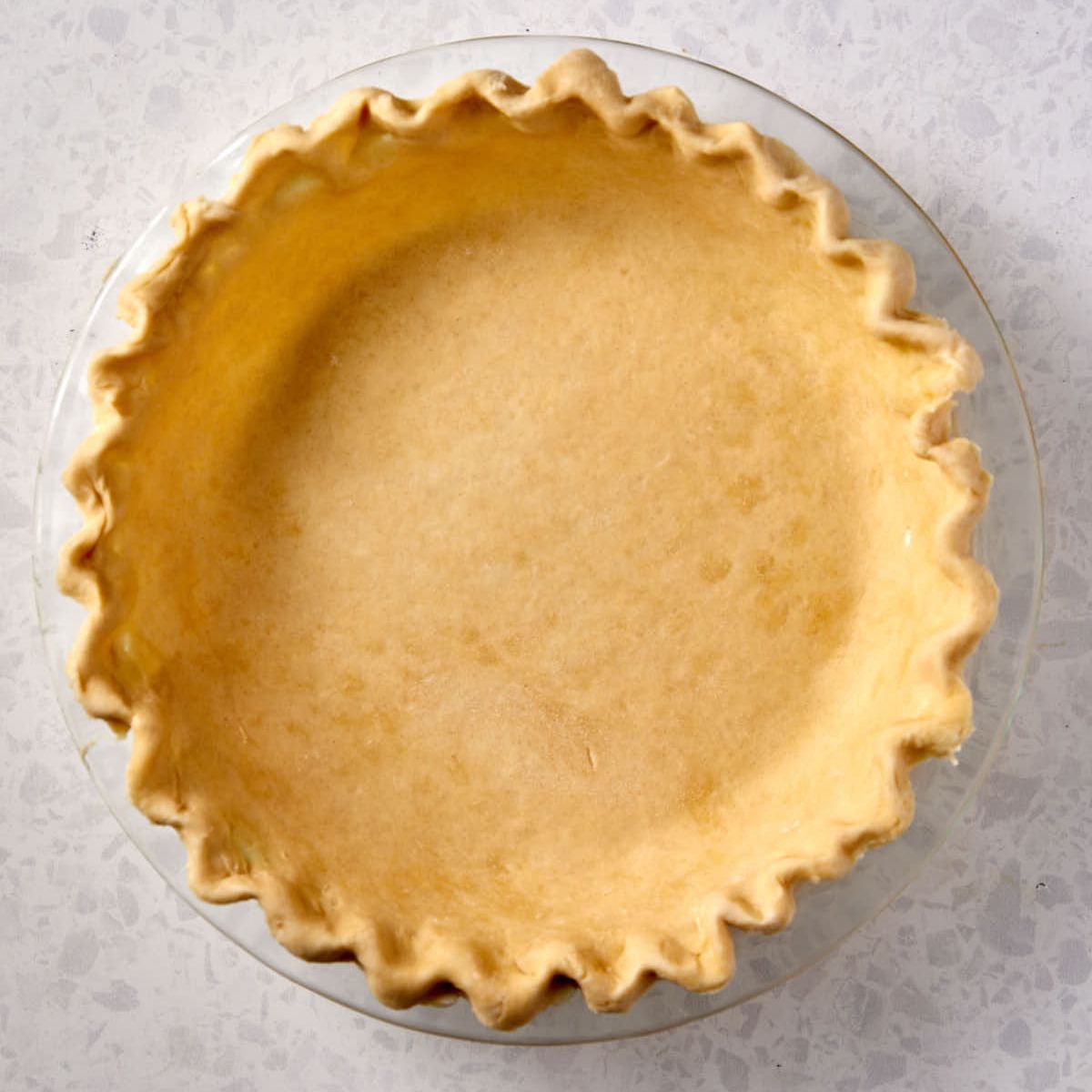 Unbaked flaky butter pie crust crimped in a 9-inch glass pie dish.