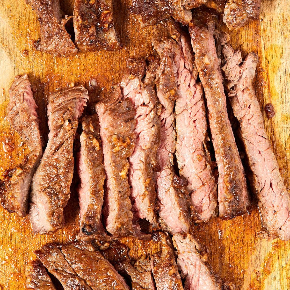 Sheet pan skirt steak sliced against the grain into thin strips, pink in the middle.