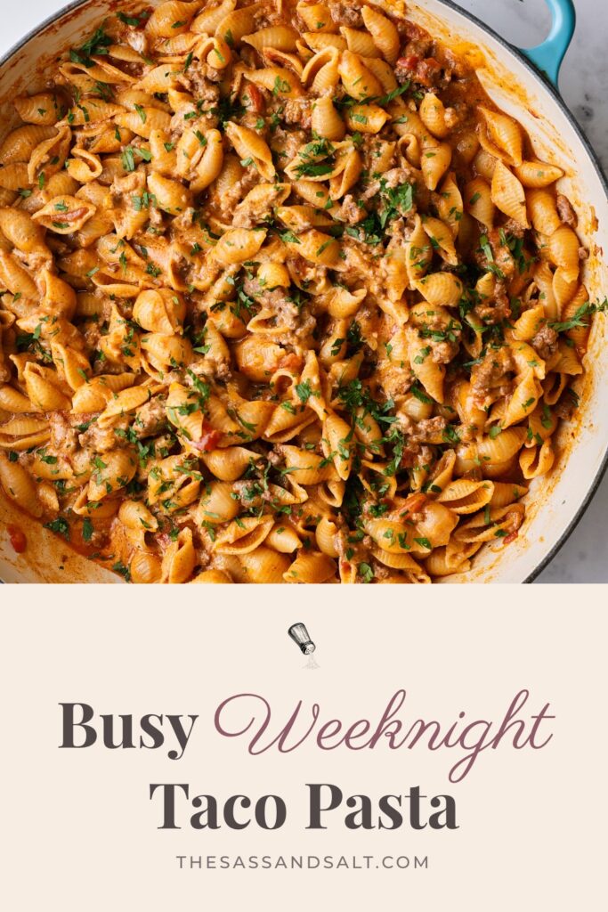 A skillet of cheesy taco pasta garnished with cilantro, with text below reading “Busy Weeknight Taco Pasta” and the website URL.