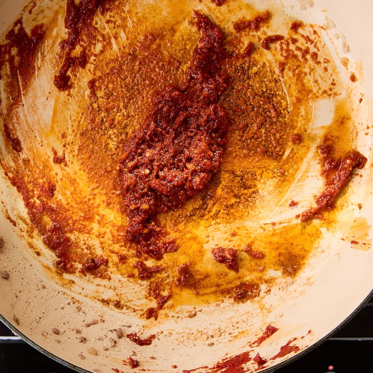 Tomato paste and taco seasoning blooming in beef fat, turning deep brick red.