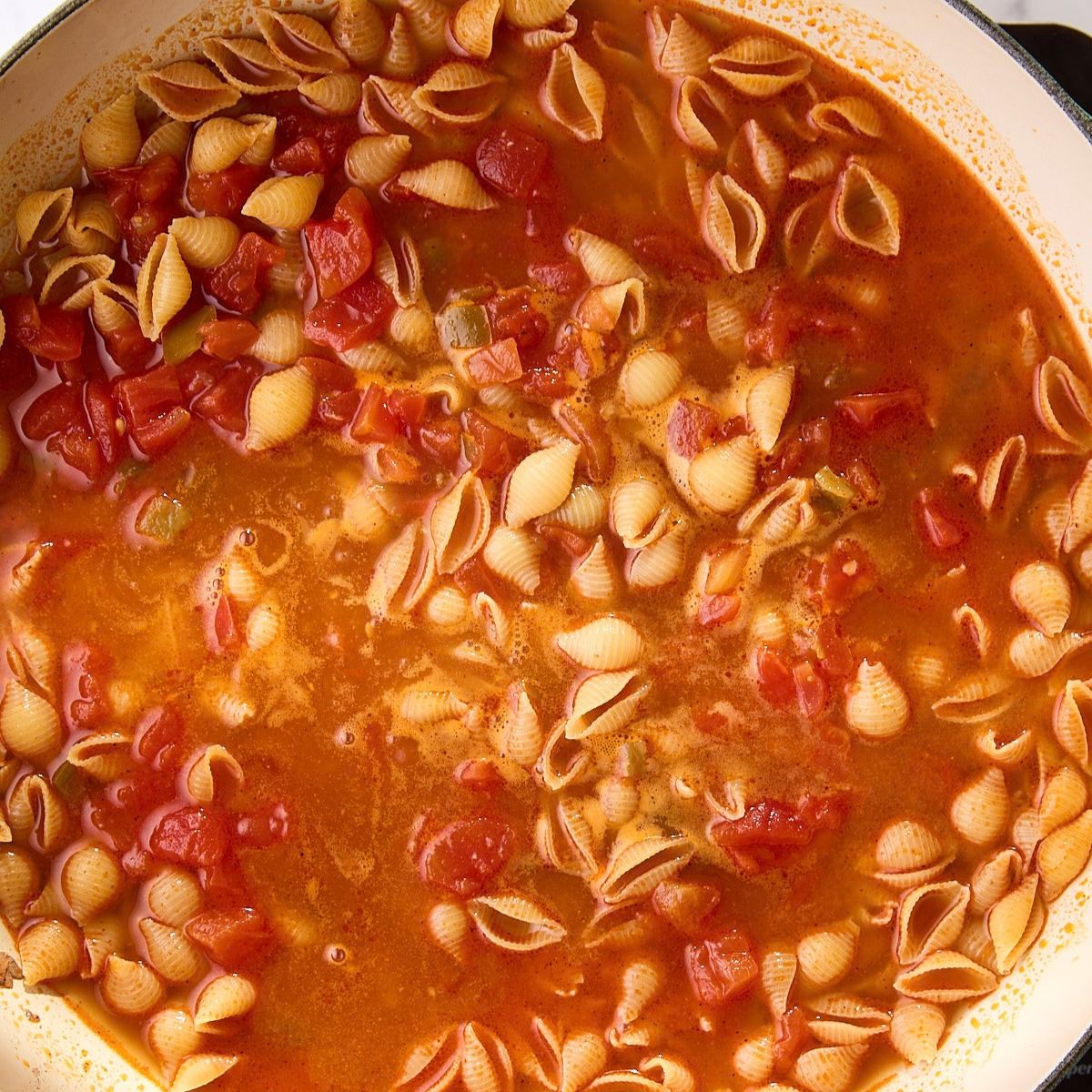 Pasta shells submerged in chicken broth and Rotel diced tomatoes with green chiles.